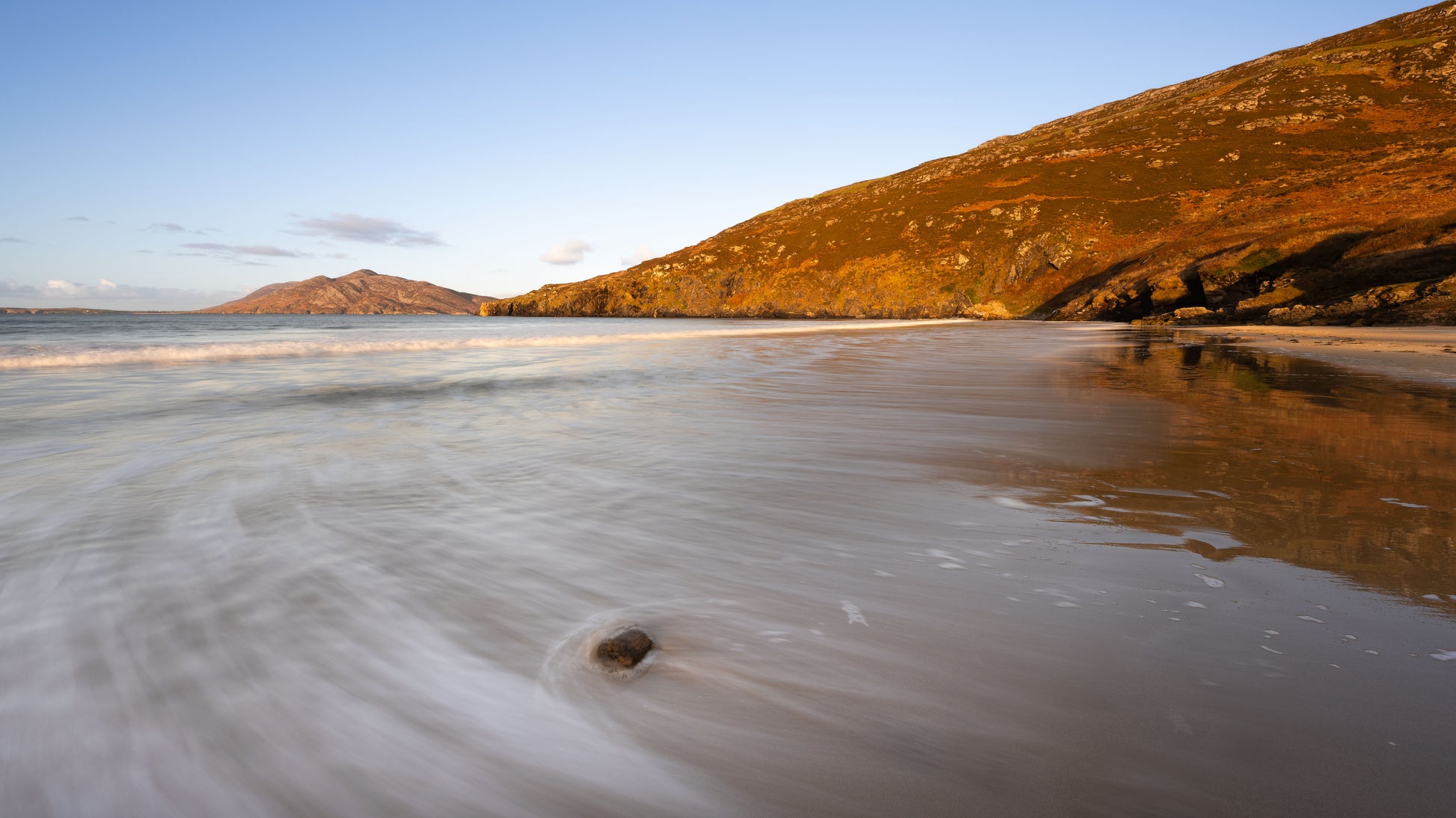 Beach with water reflections and hills in the background